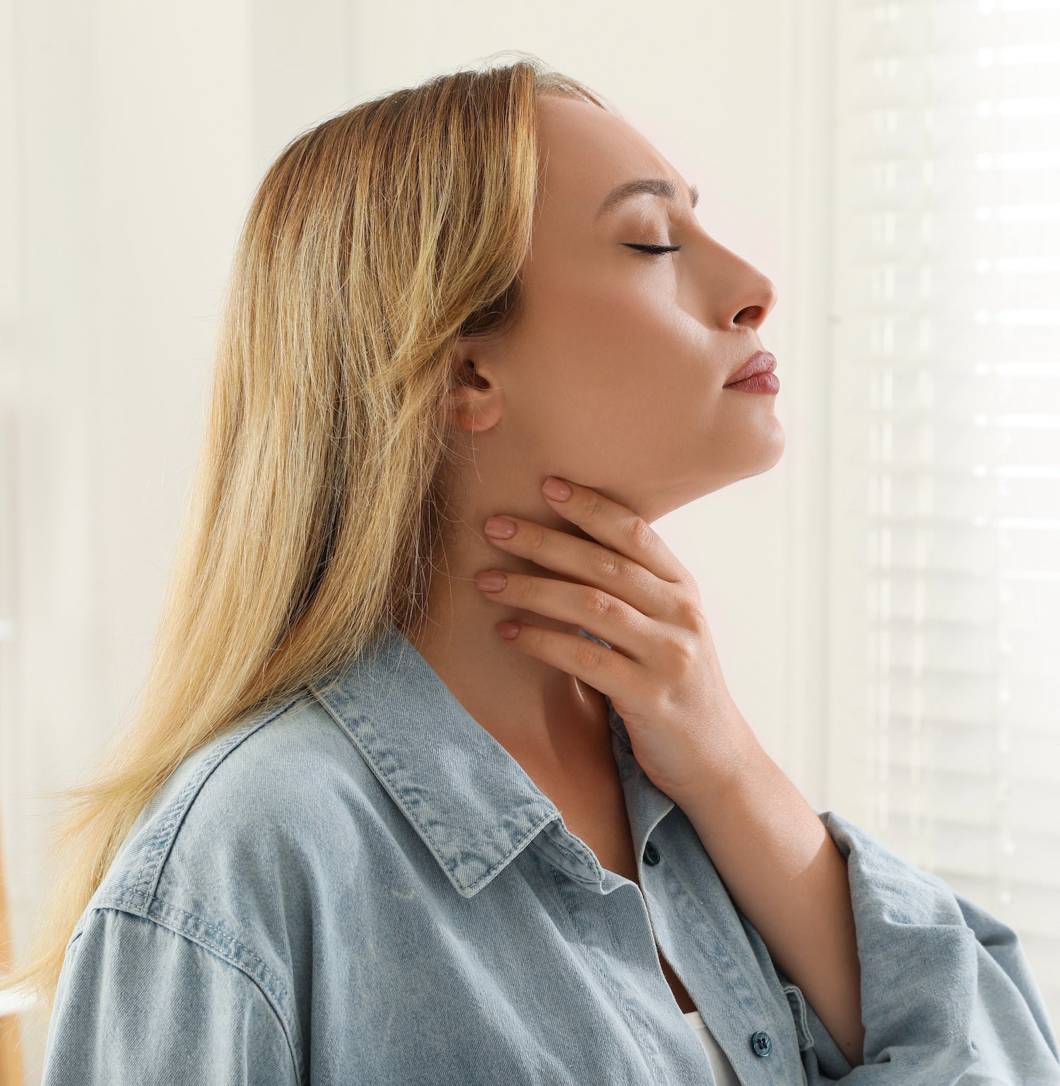 woman with thyroid hormone issues holding her thyroid with eye closed and, thinking about enclare thyroid solutions.